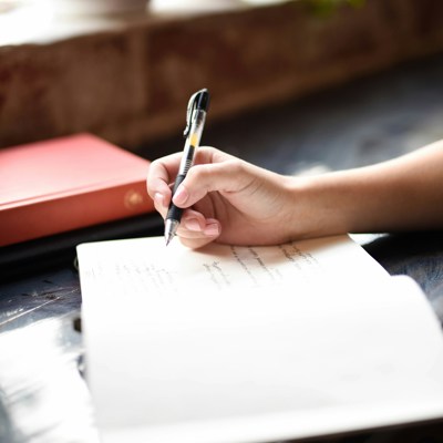 Photo credit Hannah Olinger via Unsplash - Photo of a hand writing in a journal as a strategy to quiet your mind at bedtime.